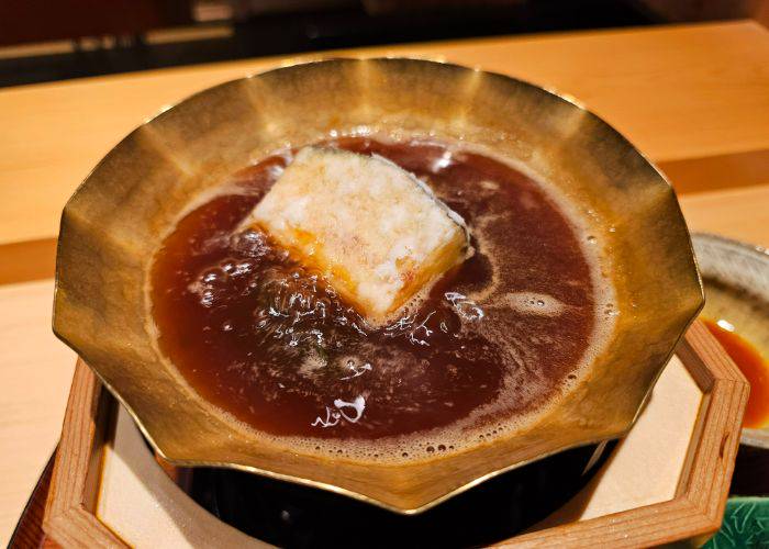 Eggplant tempura sukiyaki, bubbling away in a broth.